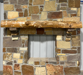 A live edge style fireplace mantel, made from ash wood, mounted on a stone wall.