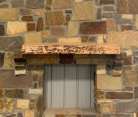 A live edge style fireplace mantel, made from birch wood, mounted on a stone wall.