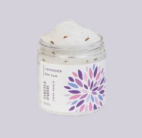 Jar of lavender bath soak with a colorful label on a light gray background