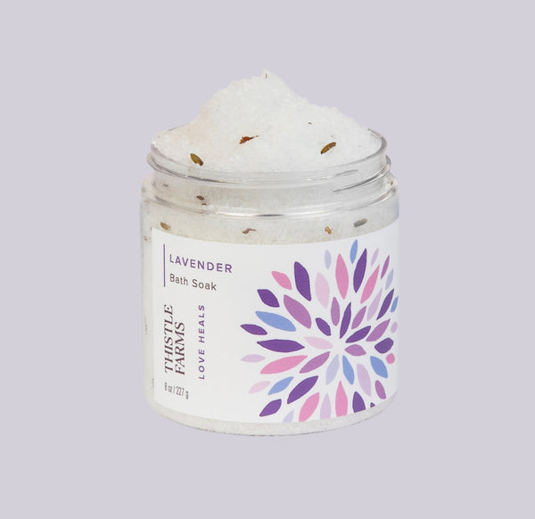 Jar of lavender bath soak with a colorful label on a light gray background
