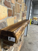 Live Edge Walnut Fireplace Mantel on a brick wall, showcasing its dark tone and smooth finish, ideal for contrasting with stone or shiplap fireplaces.