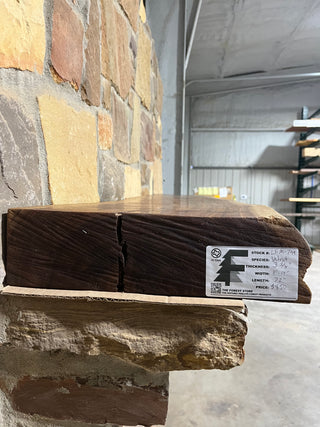 Live Edge Walnut Fireplace Mantel set against a stone wall, highlighting its natural texture and craftsmanship, ideal for complementing fireplaces with its refined, less rustic appearance.