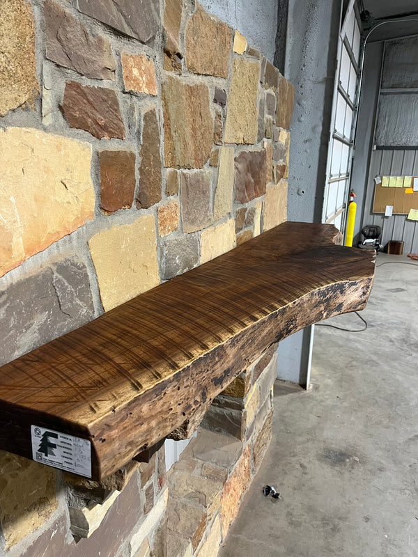 Circle sawn, live edge, rustic walnut mantel sitting on stone corbels of a fireplace