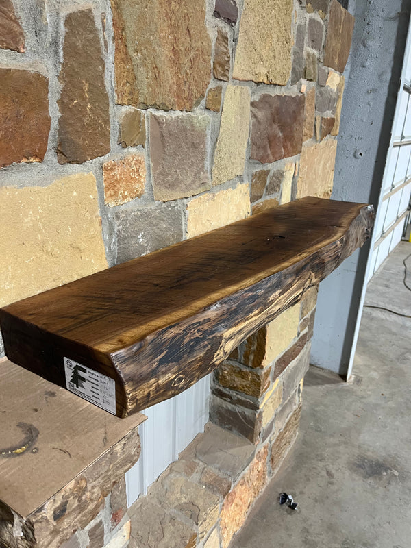 Rustic, circle sawn, live edge walnut mantel sitting on corbels of a stone fireplace