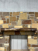 Beautiful live edge of a rustic, circle walnut mantel sitting on stone corbels of a fireplace