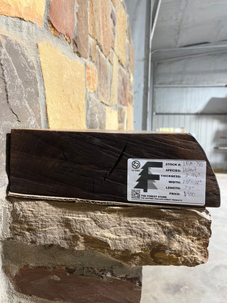 End of walnut mantel labeled and sitting on fireplace corbels