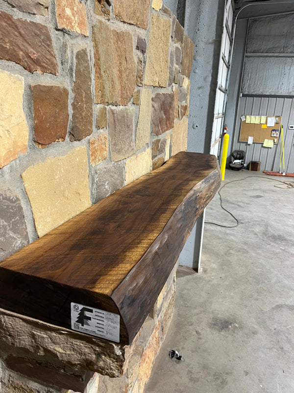 Circle sawn, walnut mantel sitting on stone fireplace corbels