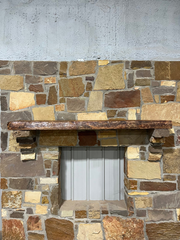 Front view of live edge cherry mantel sitting on fireplace stone corbels