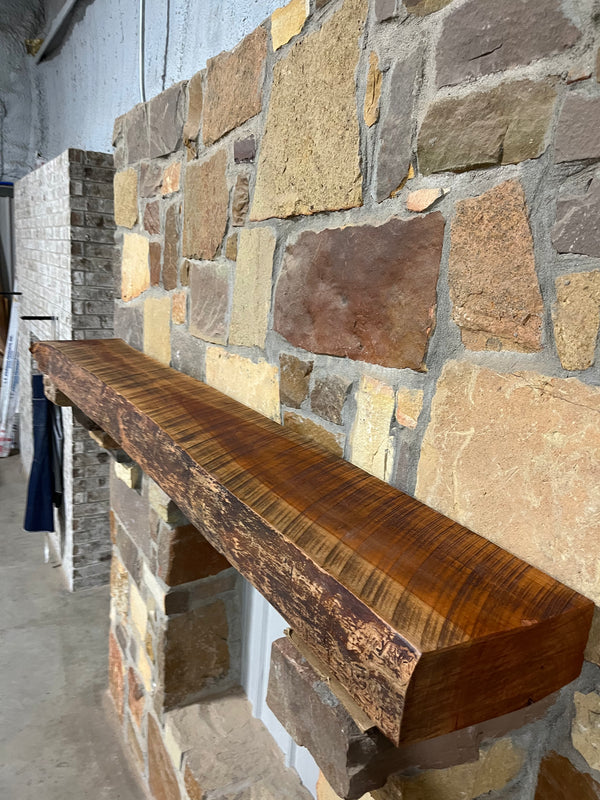 Live edge cherry mantel by the forest store sitting on stone corbels with circle sawn surface