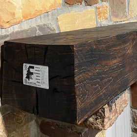 A burnt solid oak wood beam mantel mounted on a stone fireplace