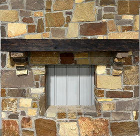 A burnt solid oak wood beam mantel mounted on a stone fireplace