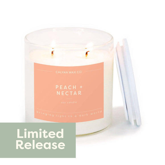 Candle with a peach-colored label on a white background, featuring 'Calvin Wax Co' and 'Peach + Nectar'.