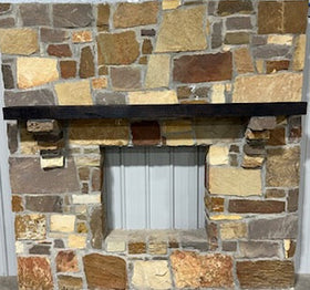 A beam style fireplace mantel, made from burned oak wood, mounted on a stone wall.