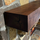 A beam style fireplace mantel, made from walnut wood, displayed on a rack.