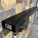 A solid Oak wood beam used for a fireplace mantel on a rock wall. 