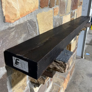 A solid Oak wood beam used for a fireplace mantel on a rock wall. 