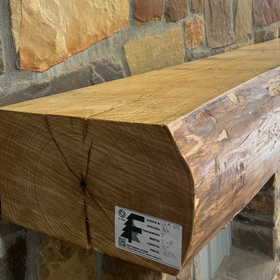 A live edge style fireplace mantel, made from ash wood, mounted on a stone wall.