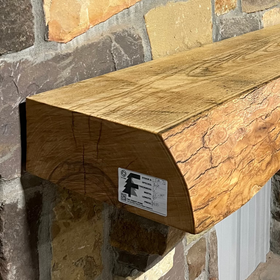 Solid live edge ash fireplace mantel mounted on a stone wall.