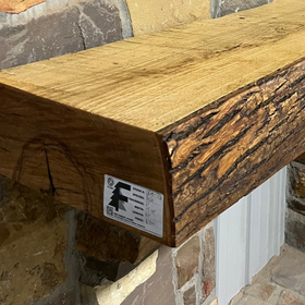 A live edge style fireplace mantel, made from ash wood, mounted on a stone wall.