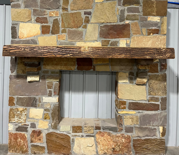 A live edge style fireplace mantel, made from ash wood, mounted on a stone wall.