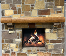 A live edge style fireplace mantel, made from ash wood, mounted on a stone wall.