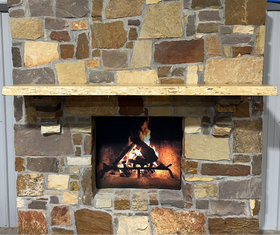 A live edge style fireplace mantel, made from ash wood, mounted on a stone wall.