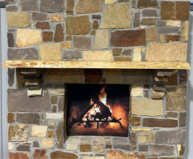 A live edge style fireplace mantel, made from ash wood, mounted on a stone wall.