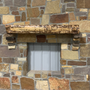A live edge style fireplace mantel, made from birch wood, mounted on a stone wall.