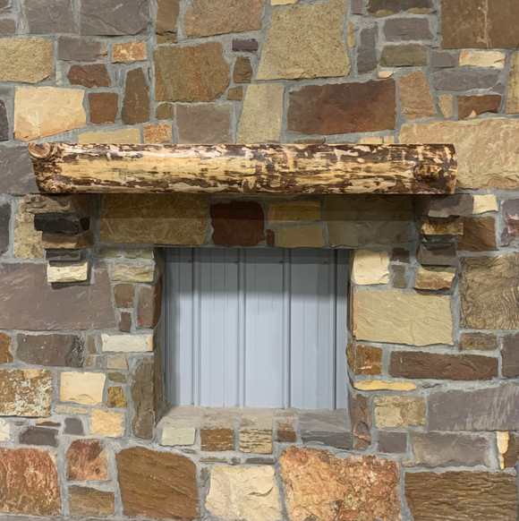 A live edge style fireplace mantel, made from birch wood, mounted on a stone wall.