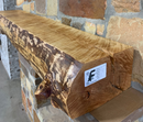 A live edge style fireplace mantel, made from birch wood, mounted on a stone wall.