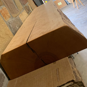 A live edge style fireplace mantel, made from birch wood, mounted on a stone wall.