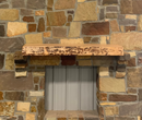 A live edge style fireplace mantel, made from birch wood, mounted on a stone wall.