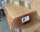 A live edge style fireplace mantel, made from birch wood, mounted on a stone wall.