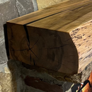 A live edge style fireplace mantel, made from birch wood, mounted on a stone wall.