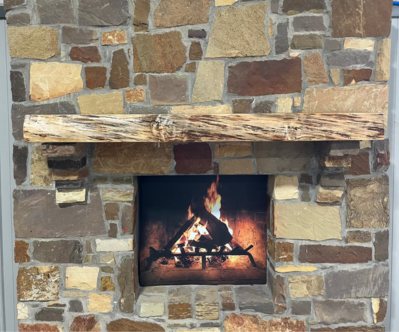 A live edge style fireplace mantel, made from birch wood, mounted on a stone wall.
