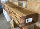 A live edge style fireplace mantel, made from birch wood, mounted on a stone wall.