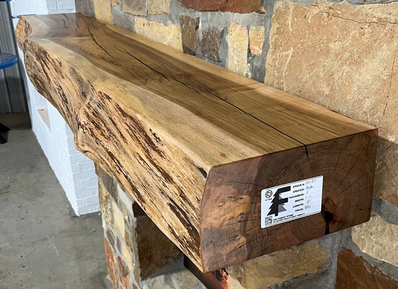 A live edge style fireplace mantel, made from birch wood, mounted on a stone wall.