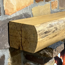 A live edge style fireplace mantel, made from birch wood, mounted on a stone wall.