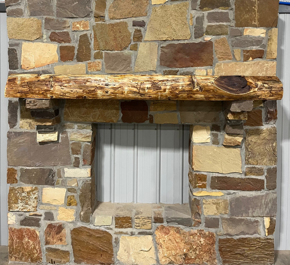 A live edge style fireplace mantel, made from bois d'arc wood, mounted on a stone wall.