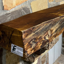 A live edge style fireplace mantel, made from bois d'arc wood, mounted on a stone wall.
