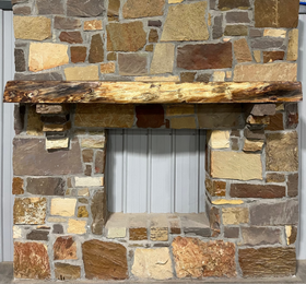 A live edge style fireplace mantel, made from bois d'arc wood, mounted on a stone wall.