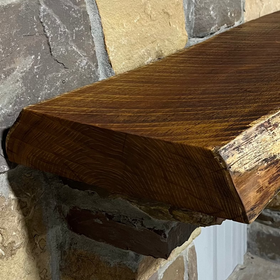 A live edge style fireplace mantel, made from bois d'arc wood, mounted on a stone wall.