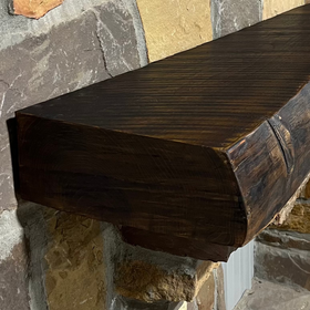 Solid live edge bois d'arc fireplace mantel mounted on a stone wall.
