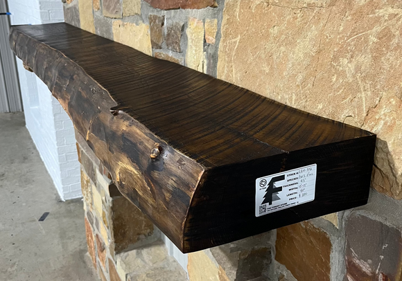Solid live edge bois d'arc fireplace mantel mounted on a stone wall.
