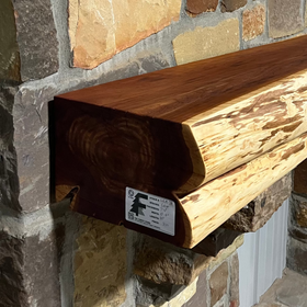 A live edge style fireplace mantel, made from cedar wood, mounted on a stone wall.
