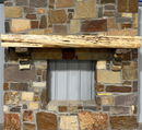 A live edge style fireplace mantel, made from cedar wood, mounted on a stone wall.
