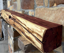 A live edge style fireplace mantel, made from cedar wood, mounted on a stone wall.
