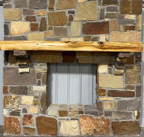 A live edge style fireplace mantel, made from cedar wood, mounted on a stone wall.