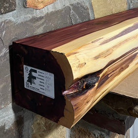 A live edge style fireplace mantel, made from cedar wood, mounted on a stone wall.
