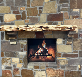 A live edge style fireplace mantel, made from cedar wood, mounted on a stone wall.
